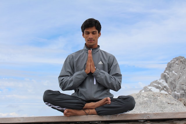 Man meditating on bench near the mountains